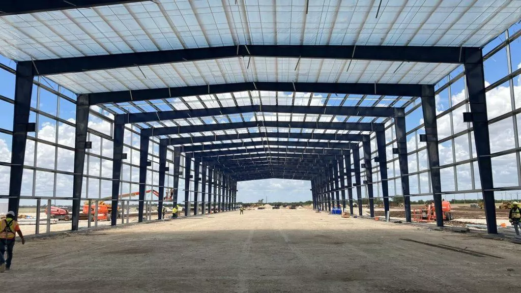 Pre-engineered building steel structure under erection with arched roof trusses against a blue sky